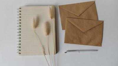 Brown envelopes and a notebook with a pen laid out on a white surface