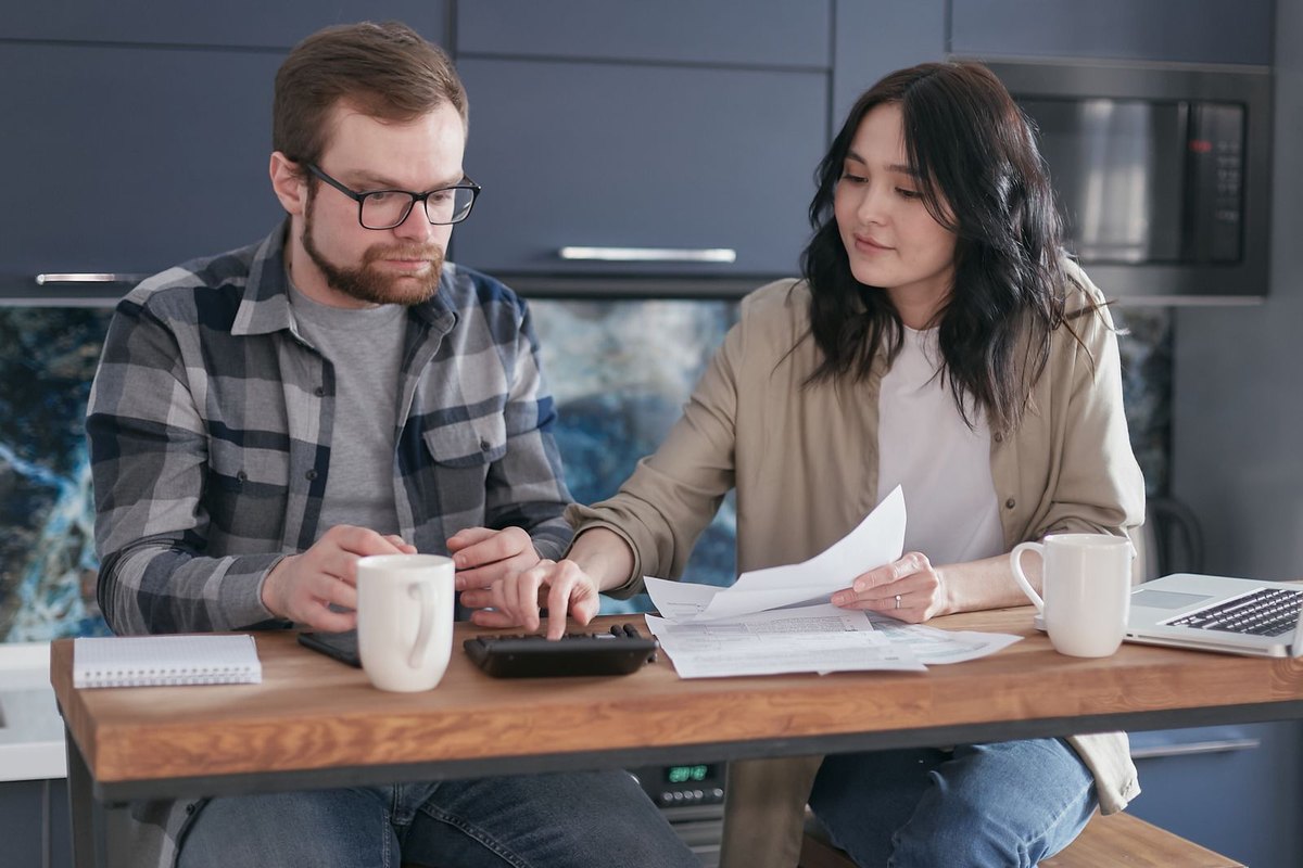 A couple sitting at home going over documents with a calculator