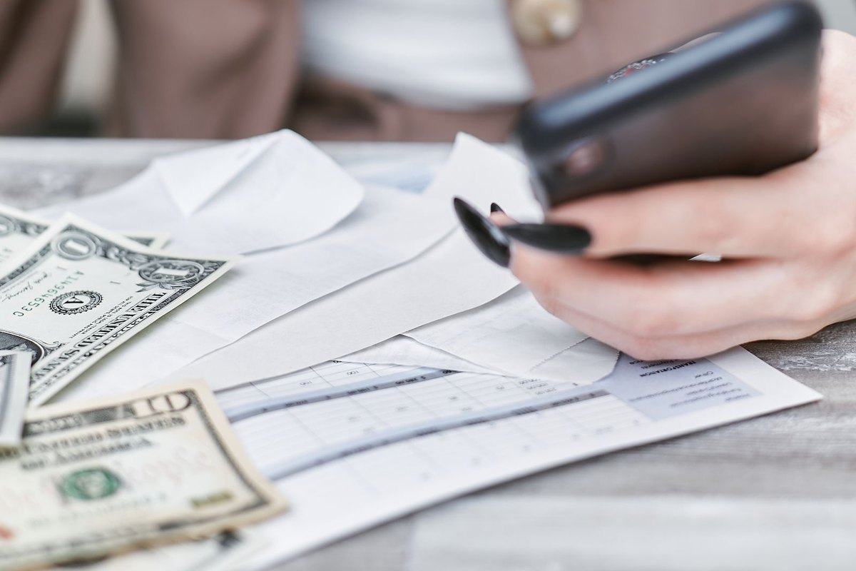 A woman using a smartphone while holding cash