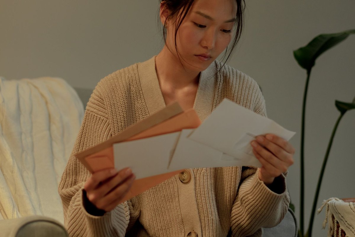 A woman in an armchair reading letters