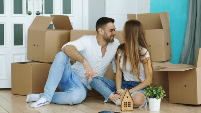 A smiling couple sitting among boxes on moving day