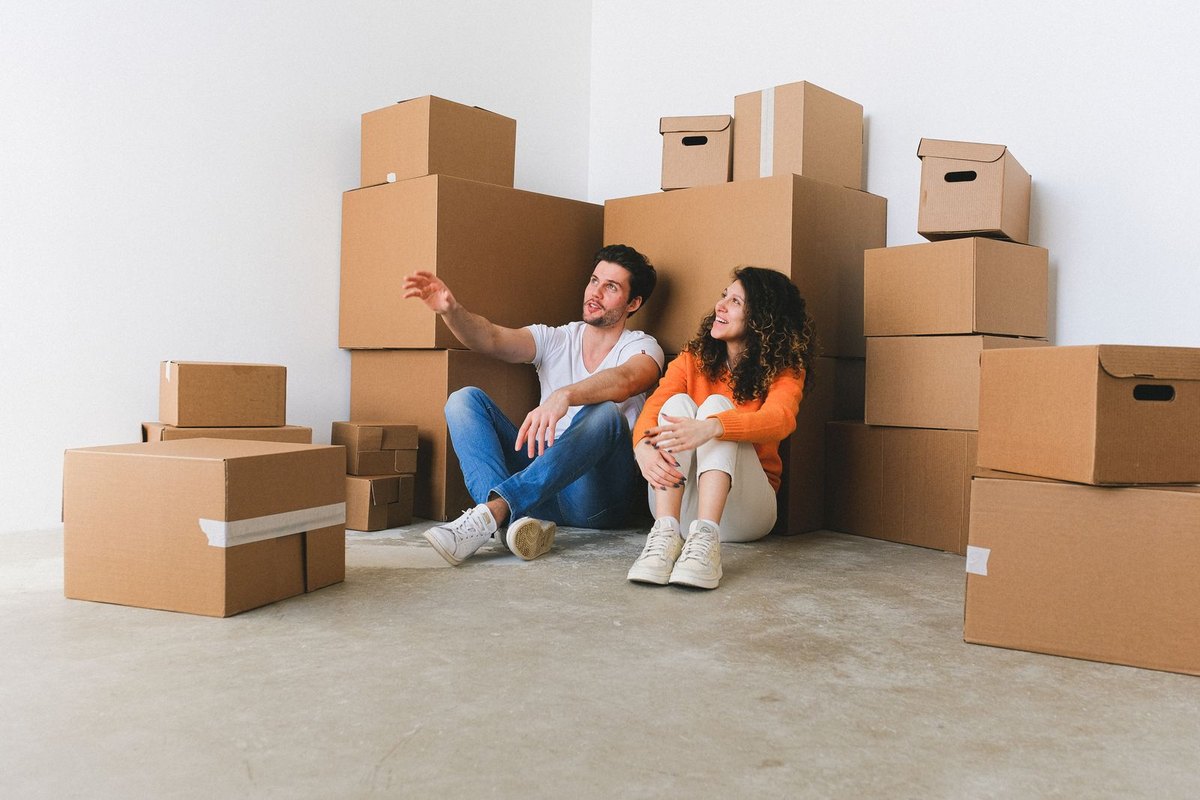 A couple sitting on the floor among moving boxes in their new home