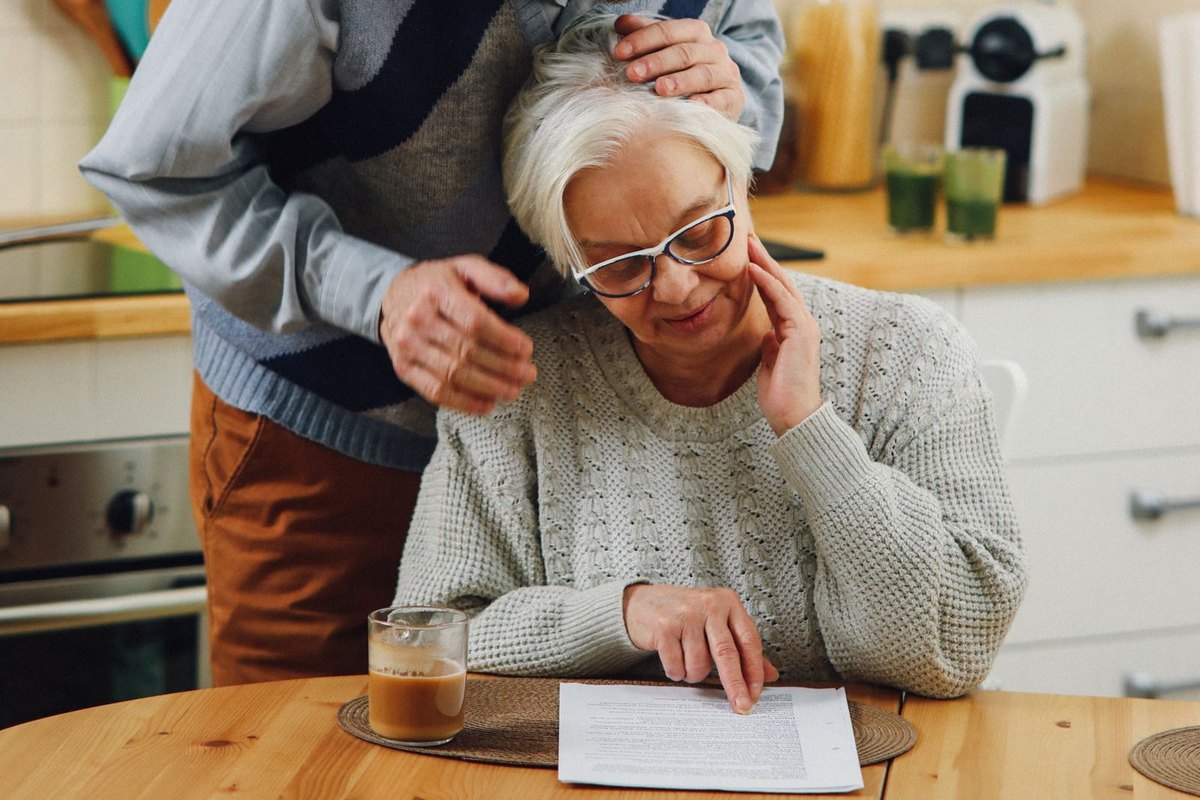 An older couple reading a document together in their kitchen