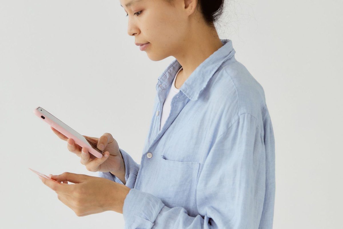 A woman using her phone while holding a credit card
