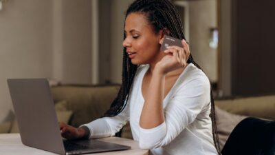 A woman holding a credit card while using a laptop