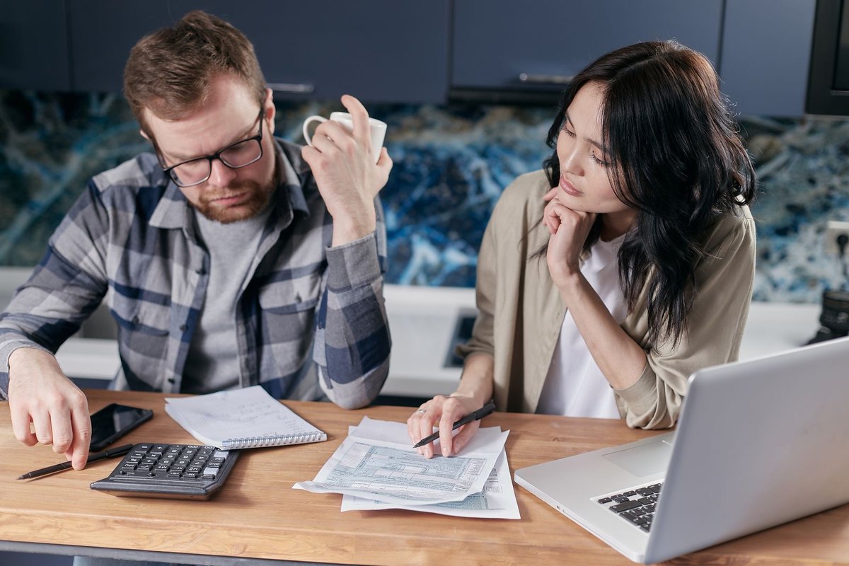 A couple reviewing paperwork on a laptop at home