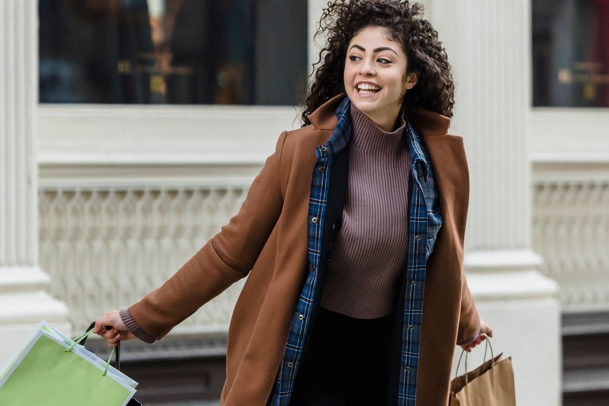 A smiling woman carrying shopping bags on a city street