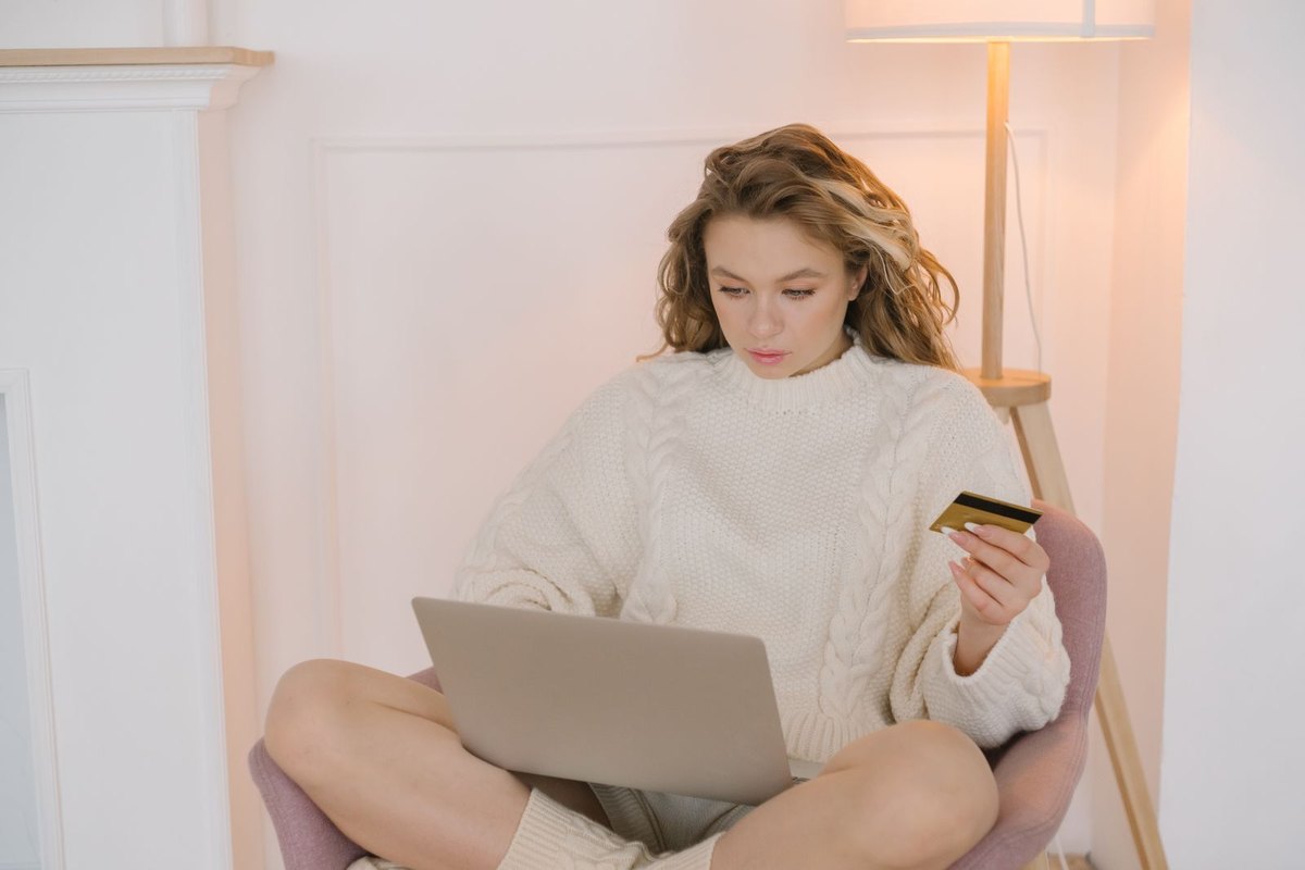 A woman shopping online on her laptop with a credit card in hand