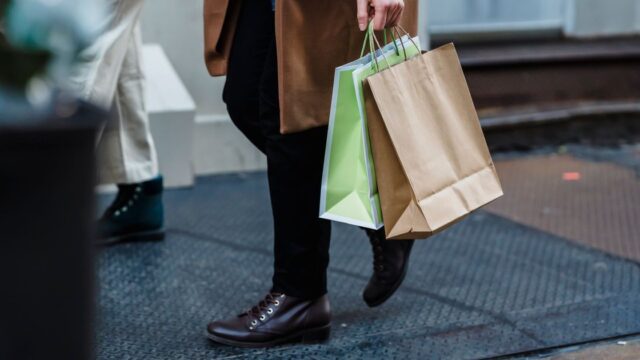 A woman walking down a city street carrying paper shopping bags