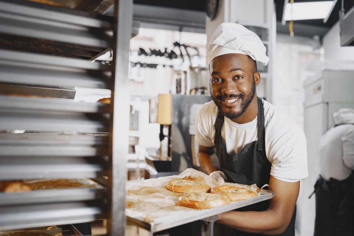 A baker holding a tray of freshly baked bread