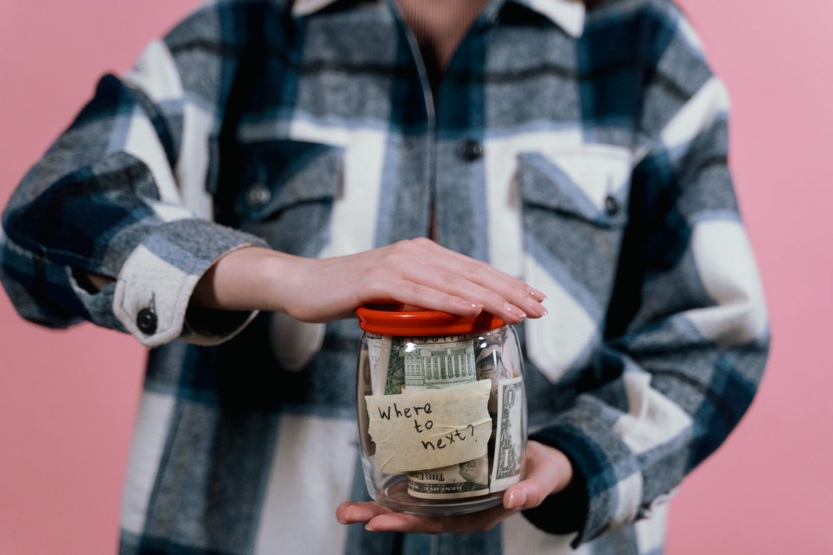 A woman holding a glass jar of banknotes