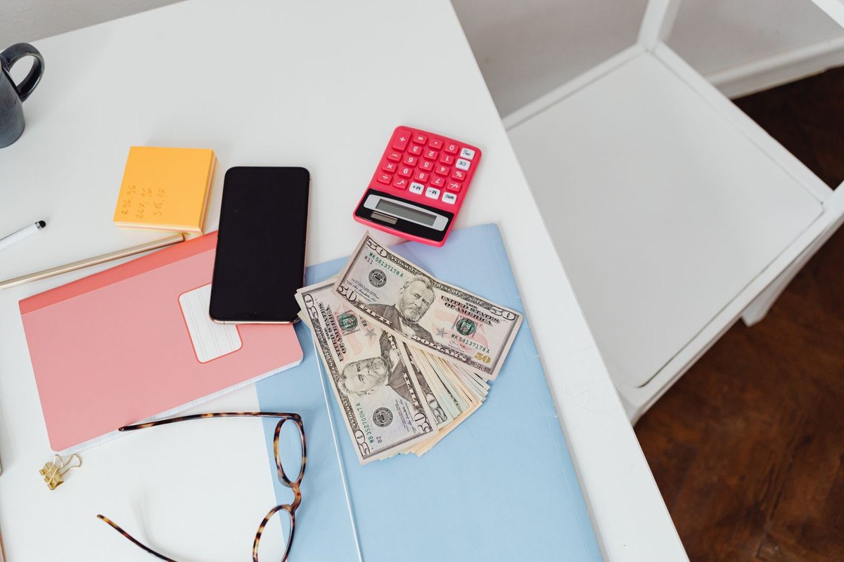 Paper bills, a calculator and glasses on a desk