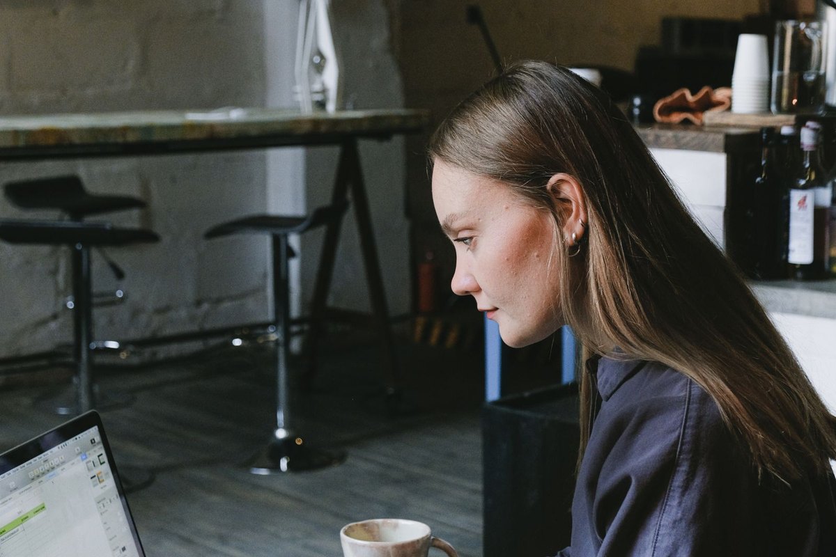 A young woman working on a laptop in a café