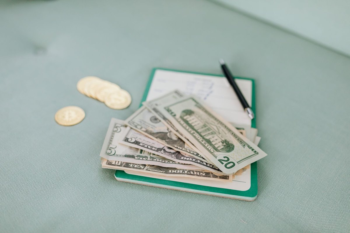 Dollar bills and coins on a journal beside a pen