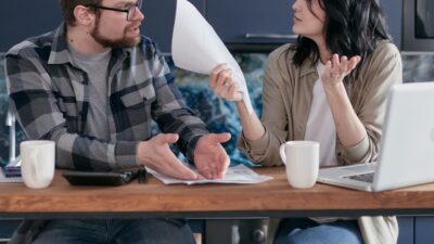A man and woman at a table with a laptop and papers