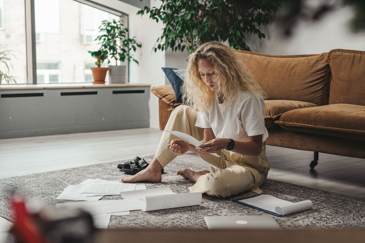 A woman sitting on the floor at home with paperwork