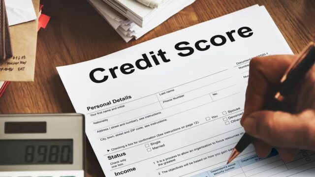 A hand signing a credit score form next to a calculator