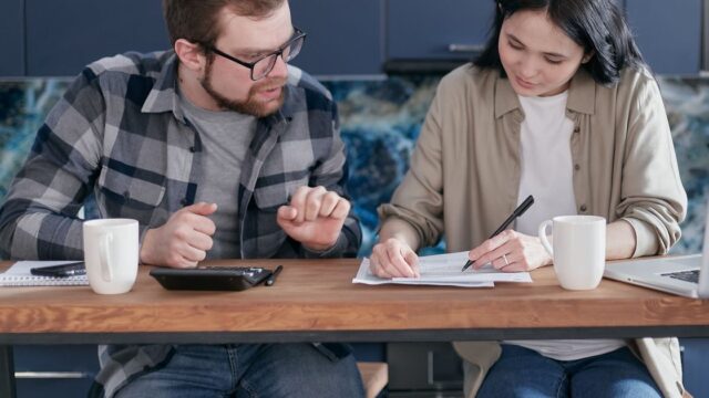 A couple at a table with documents, a laptop and a calculator