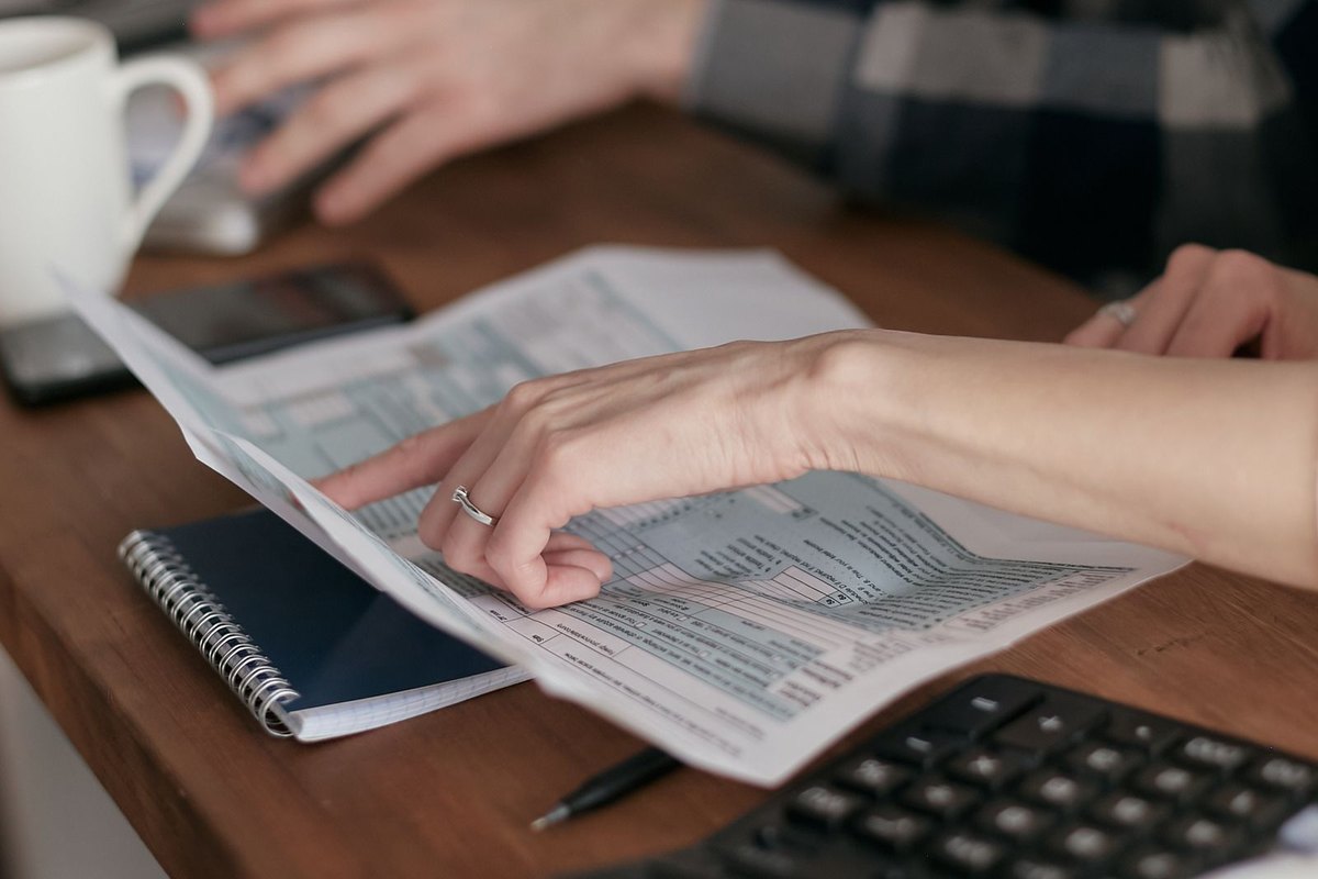 Two people looking over documents and a calculator on a wooden table