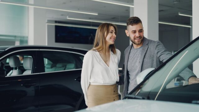 A smiling couple looking at cars in a dealership