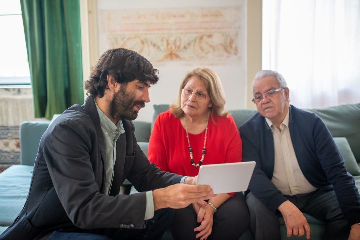 A financial adviser showing a tablet to an older couple in their living room