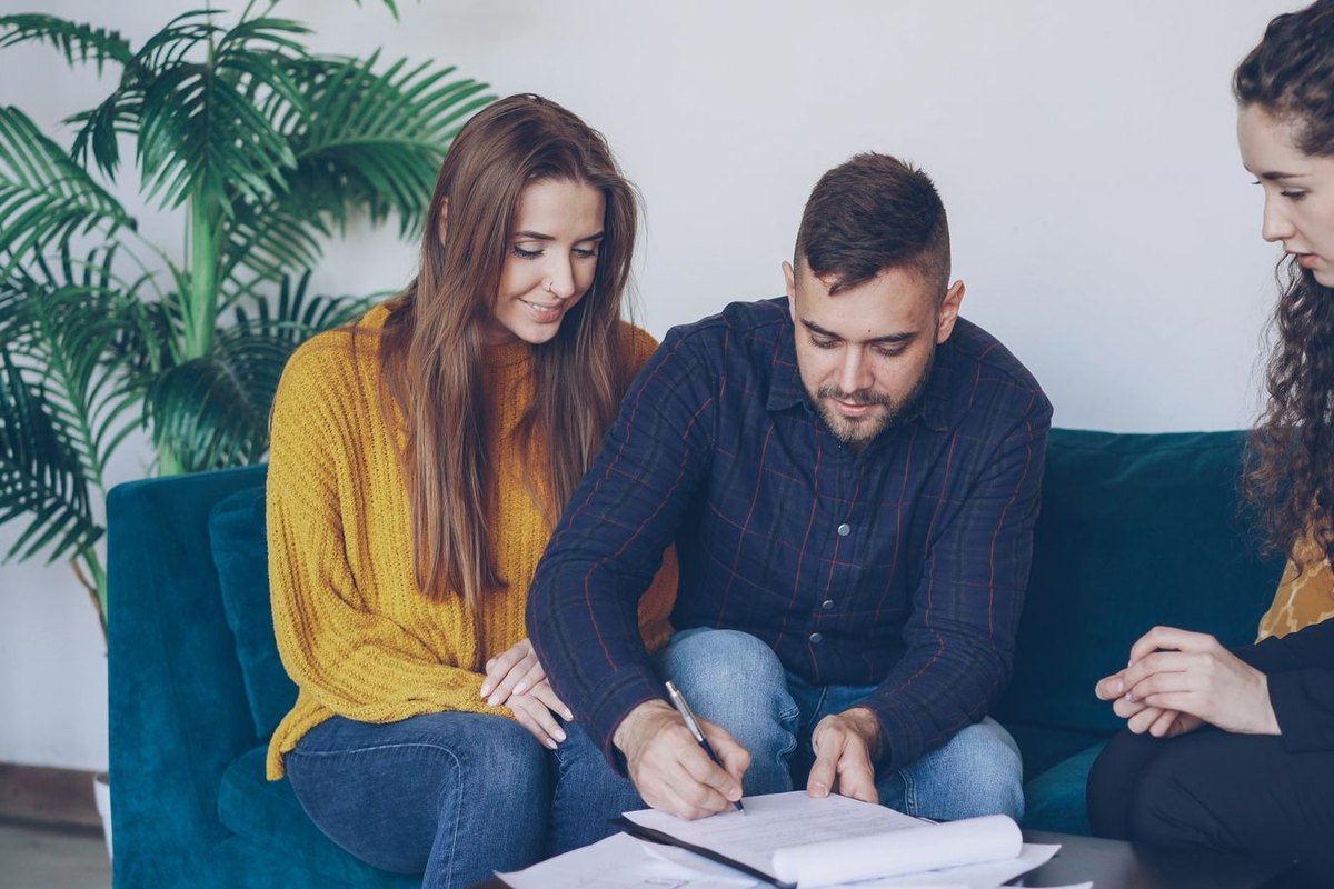 A young couple signing paperwork with a financial adviser