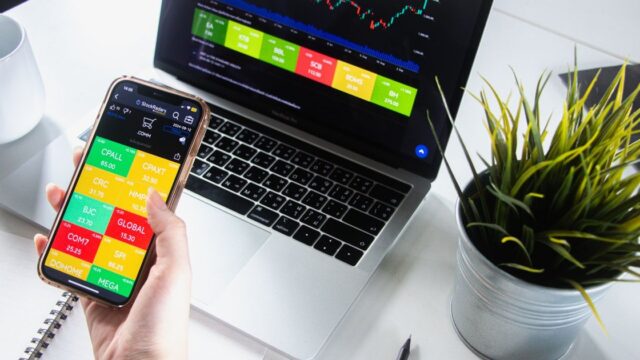A person checking stock market charts on a phone and laptop