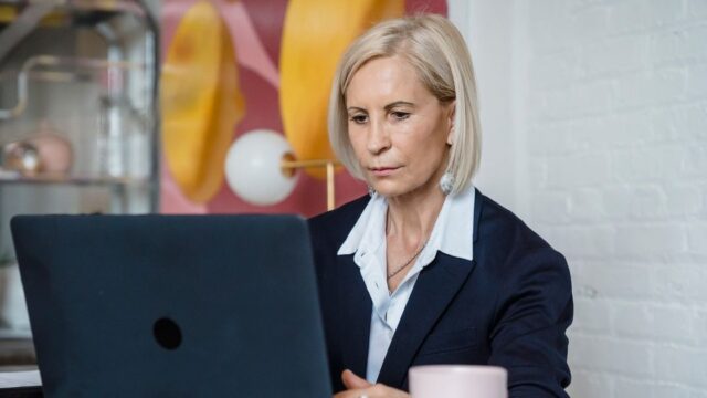 A woman in smart clothes working on a laptop in an office