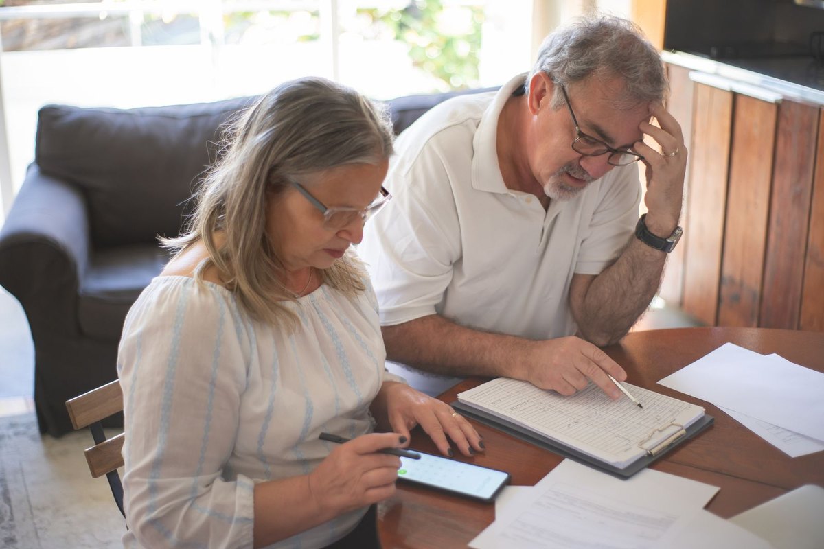 An older couple at a table with documents and a smartphone